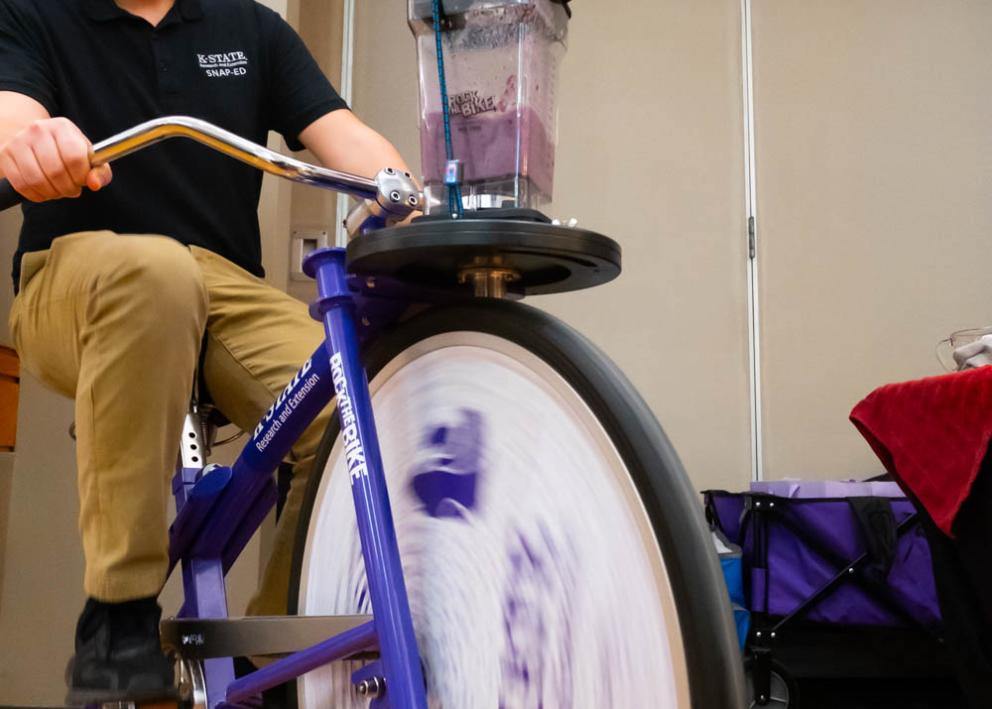 A vendor riding an exercise bike designed to blend a smoothie